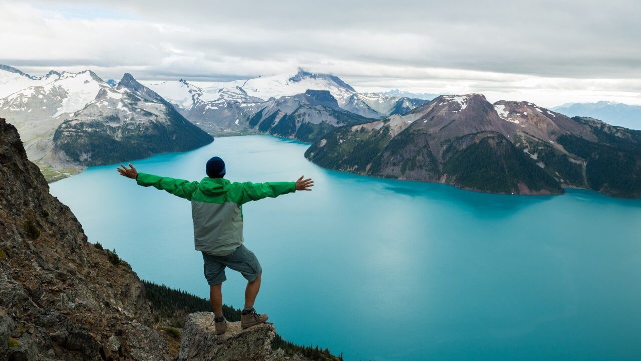 Man standing on the mountain and blue lake down side